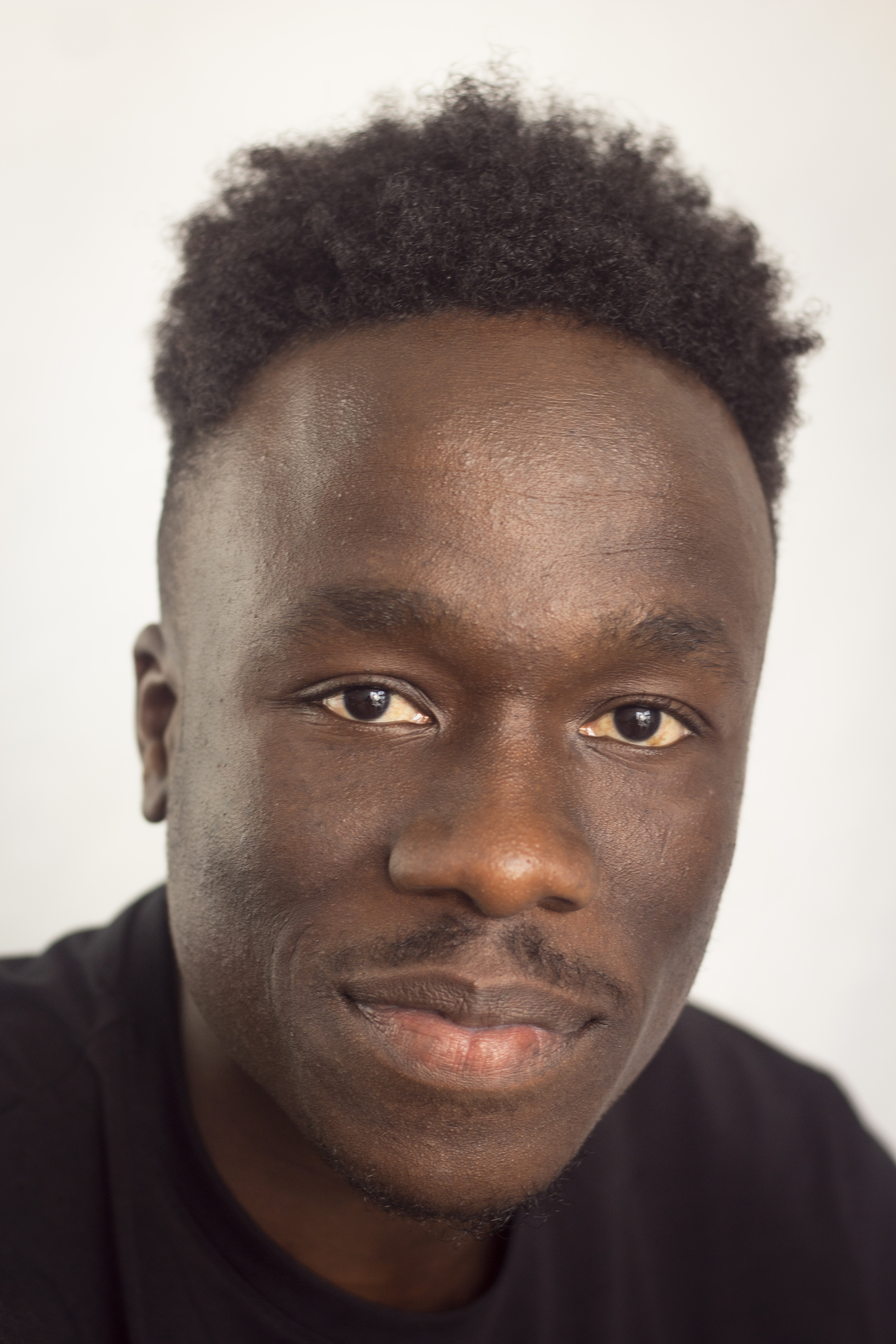 two female figures stand facing each other in front of a stone wall and natue backdrop